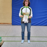 Gudrun Strauss steht in Turnhalle und hält ihre Urkunde in der Hand