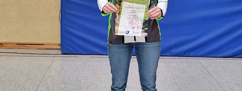 Gudrun Strauss steht in Turnhalle und hält ihre Urkunde in der Hand