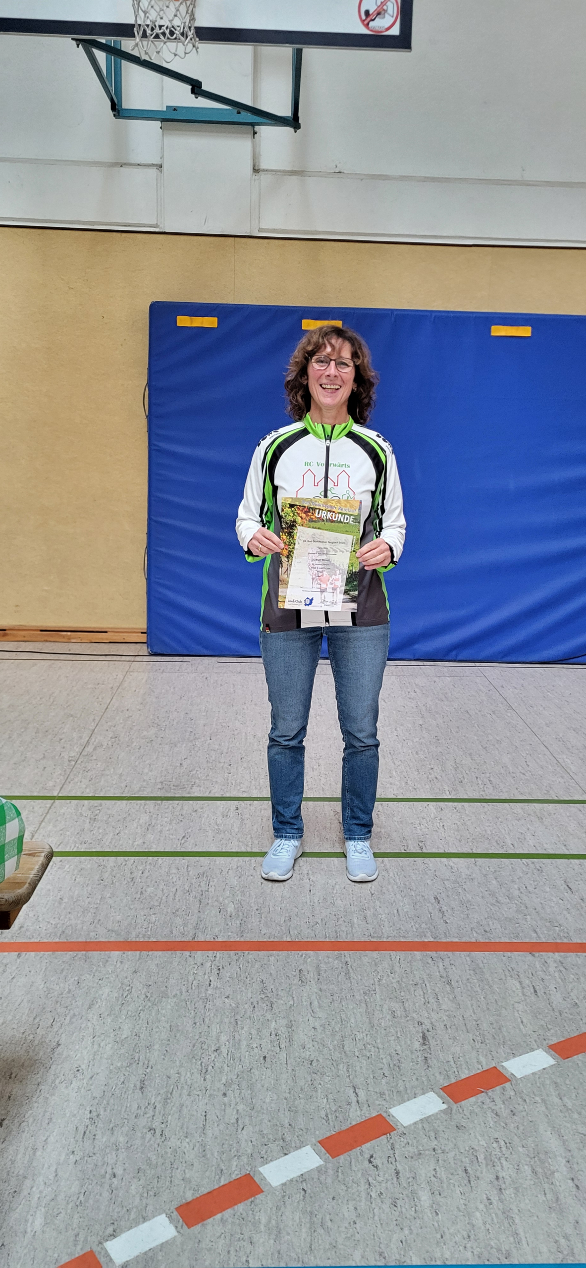 Gudrun Strauss steht in Turnhalle und hält ihre Urkunde in der Hand